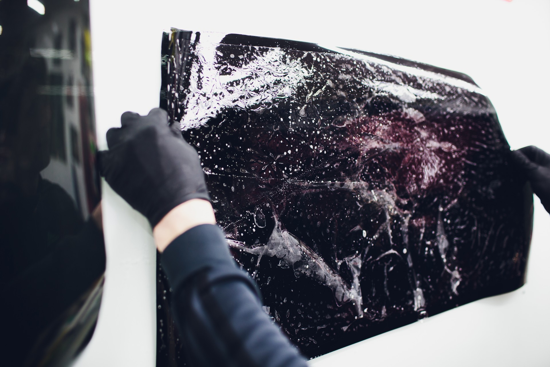 Applying tinting foil on car window in garage