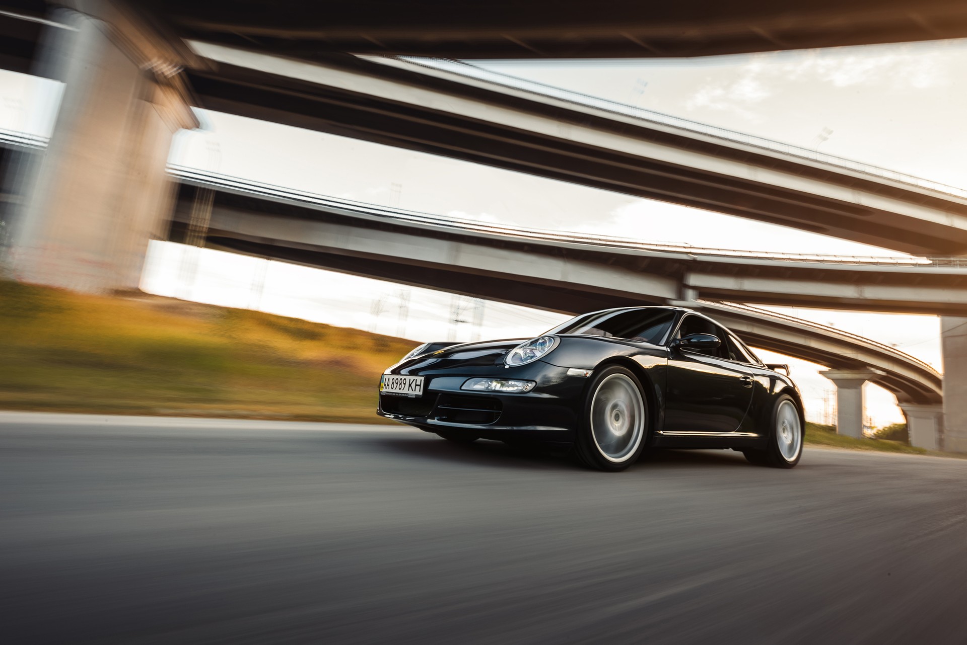 Porsche 997 driving under the bridge at sunset