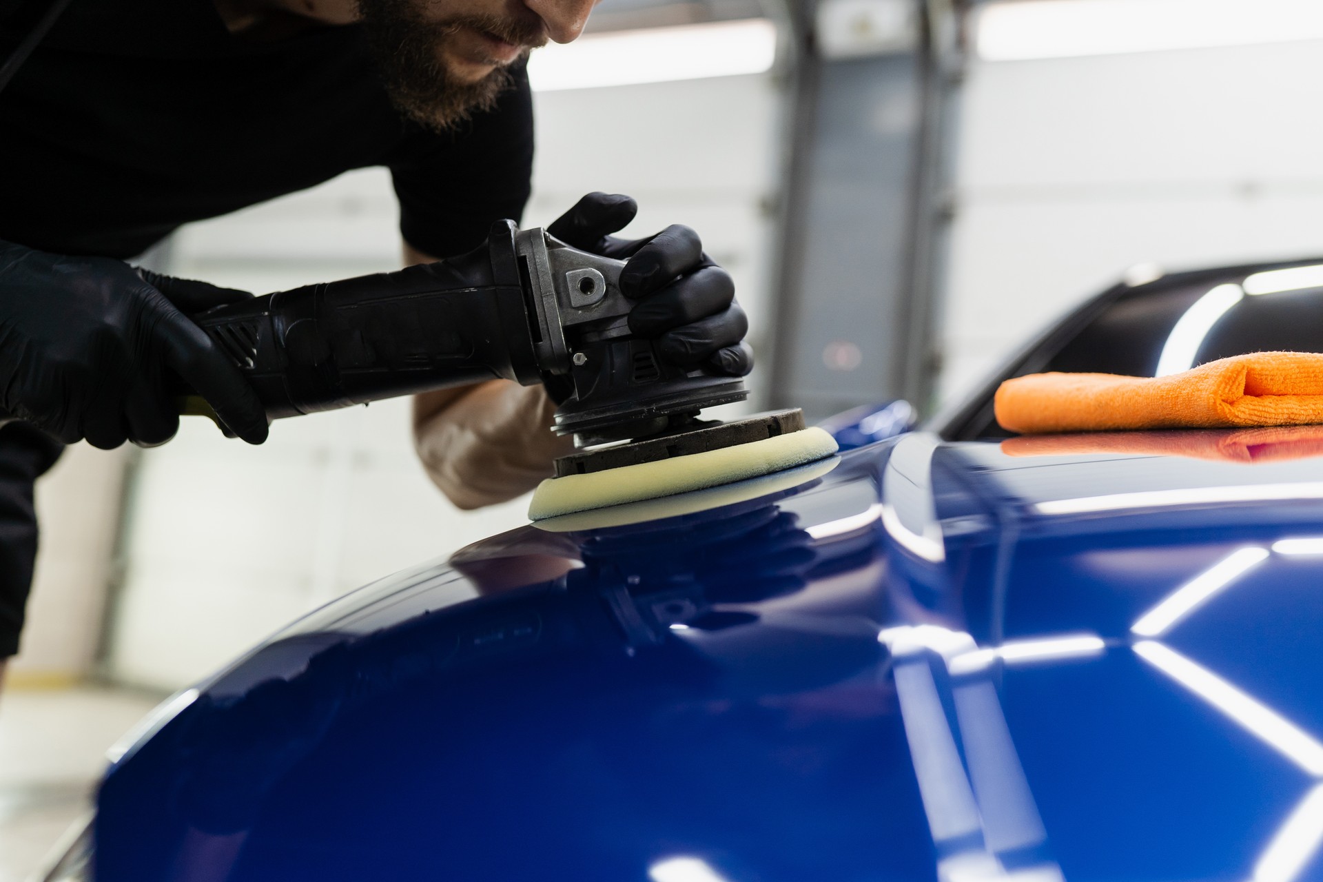 Abrasive paste car polishing with orbital polisher for remove scratches. Worker of detailing auto service making final polishing for car.