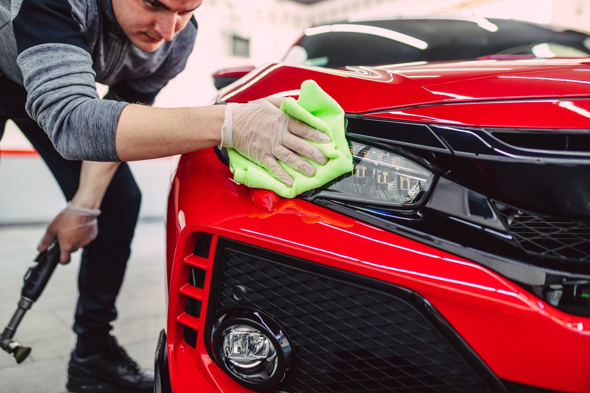 A man cleaning car with cloth, car detailing (or valeting) concept. Selective focus.  A man cleaning car with cloth, car detailing (or valeting) concept. Selective focus.